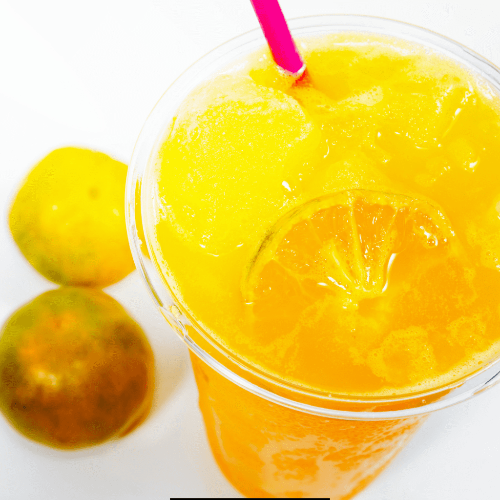 Sonic Orange Cloudsicle Slush Float topped with ice and two oranges behind